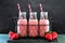 Strawberry smoothies in bottles in a vintage wire basket over dark slate