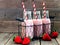 Strawberry smoothies in milk bottles against a rustic wood background