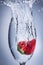 Strawberry splash plunge into water in a wine glass.
