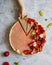 Strawberry tart on a grey background, water on top. A child`s hand reaches for the cut piece.