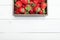 Strawberry wooden box on white wooden background, copy space for text