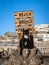 A stray cat posing on a tree stump in front of a sign pointing at the beach in Puerto Rico, Gran Canaria in Spain