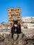 A stray cat posing on a tree stump in front of a sign pointing at the beach in Puerto Rico, Gran Canaria in Spain