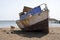 Stray dog â€‹â€‹walks next to an old crooked fishing boat, on the city beach of Praia, island of Santiago, Cape Verde, Cabo Verde