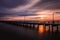 Streaking clouds over a long fishing pier as the sun rises over the horizon. Captree State Park, Long Island NY