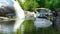 Stream clean water in river flowing between large stones and boulders. Plants tropical forest on background stony river