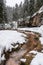 A stream flowing in to a peaceful river between snowy banks