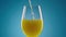 A stream of freshly squeezed natural orange juice poured into glass. Exotic yellow citrus nectar or lemonade in glass on