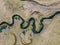 A stream meanders through a green valley, with natural twists and curves. Meandering watercourse Top view. Aerial view