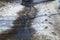 Stream of melted snow on a path with shoeprints