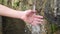 Stream of refreshing clear water from a natural mountain spring splashes a teenage hand.