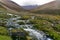 Stream in a rocky valley in the mountains with hiker