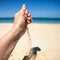 A stream of sand falls from the hand of a woman on a sandy beach