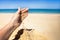 A stream of sand falls from the hand of a woman on a sandy beach