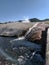 Stream of steaming water flowing into river at Yellowstone National Park