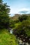 Stream in a valley and in the background a mountain with lenticular clouds on its summit. Bariloche, Argentina. Vertical