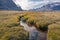 Stream winds through wild arctic landscape in Akshayuk Pass, Baffin Island, Canada. Moss valley floor and dramatic