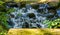 Streaming water over rocks in closeup, beautiful garden architecture, nature background of a tiny waterfall