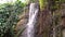 Streaming waterfall of a cliff in a tropical nature scenery, water in motion