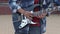 Street artist plays electric guitar live in busy city street Close up on the hands