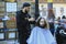 Street barber doing young man`s hair on the street, people walking on a background