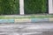 A street border painted white and blue against a road and green foliage in a summer close-up. Road safety, minimalism.