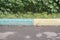 A street border painted white and blue against a road and green foliage in a summer close-up. Road safety, minimalism.