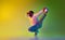 Street dancer. Young man with dreads hairdo, in casual clothes dancing breakdance against gradient yellow green studio