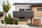 Street facades of an urbanization with semi-detached single-family homes with trees and decorative hedges