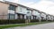 A street of family houses in suburban area with concrete side walk and asphalt road in front. Residential houses.