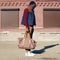 Street fashion look concept stylish african young man wearing vest jacket, sweater, bag walking in city evening, vintage colors