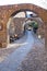 Street full of stone archs with a car in Potes