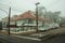 Street with houses and parked cars on a foggy day