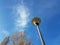 Street lamp and deciduous trees in autumn against blue sky with veil clouds