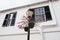 Street lamp with flower pots on house facade in Hamilton, Bermuda. Potted flowers on lighting column with stree lamp