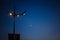 Street lamp at night against the dark blue sky and the moon.