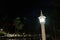 A street lamp shines on the bank of a small river at night