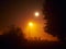 the street lamp is shining, the full moon is shining, there is a thick fog on the street