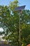 street lamp with a solar battery against a blue sky and trees