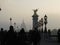 Street lamps and a tall monument on a misty afternoon on the Pont Alexandre III, Paris