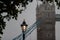 Street lantern against the Tower bridge in deep morning fog. London, the UK