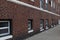 Street level view of an old brick apartment building with rows of basement and first floor windows, urban cityscape