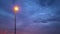 Street light that illuminates the sunset light and Black rain clouds moving rapidly across the sky