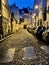 Street lights glow yellow on the house fronts and cobblestoned street on Montmartre in Paris