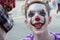 Street makeup on the face of a teenager. The boy smiles in the image of a clown with sharp teeth or a mime. Halloween holiday or