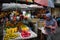 A street market in the capital with trays of exotic fruits and buyers