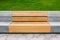 Street modern park bench. A bench made of wood and concrete against the backdrop of a lawn. Urban interior. A place to