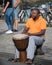 Street musician with orange shirt playing the Djembe