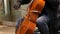 Street musician playing the cello. Cellist in gloves gently bows strings