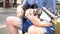 Street musician strumming guitar on the street outdoors while passerby walking by